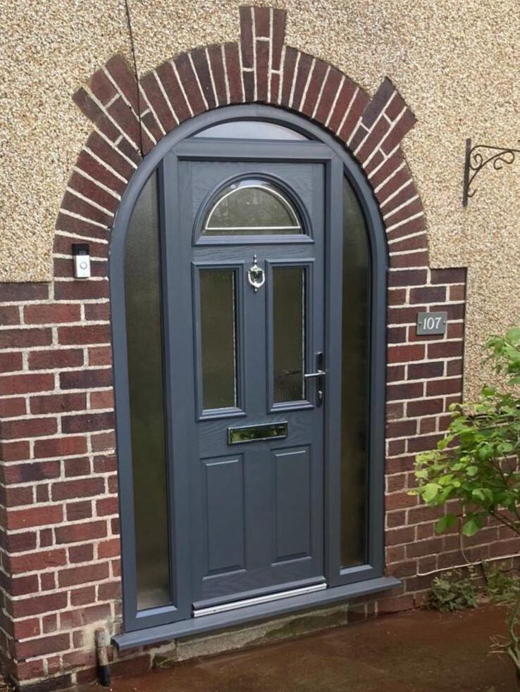 Anthracite grey composite arched front door with decorative glass panels and matching sidelights